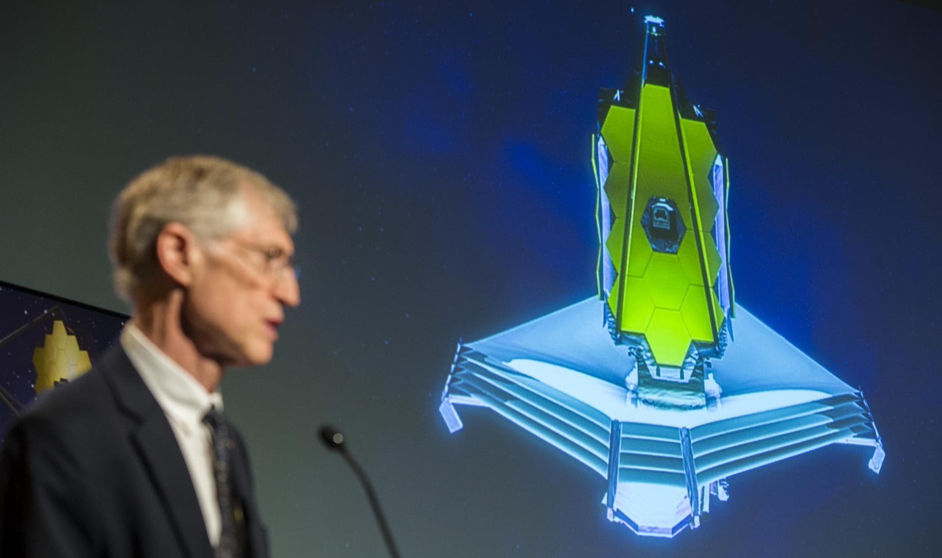An animation of the James Webb Space Telescope (JWST) is projected as John Mather, Nobel Laureate and Project Scientist for the JWST speaks during a panel discussion on the search for life beyond Eart