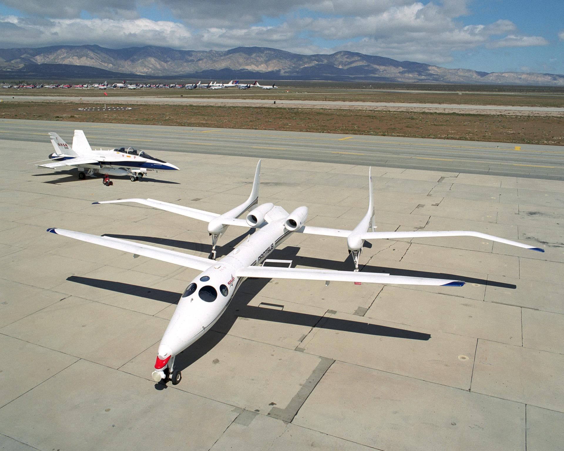 Scaled Composites' Proteus aircraft and an F/A-18 Hornet from NASA's Dryden Flight Research Center at Mojave Airport in Southern California.  The unique tandem-wing Proteus was the testbed for a serie