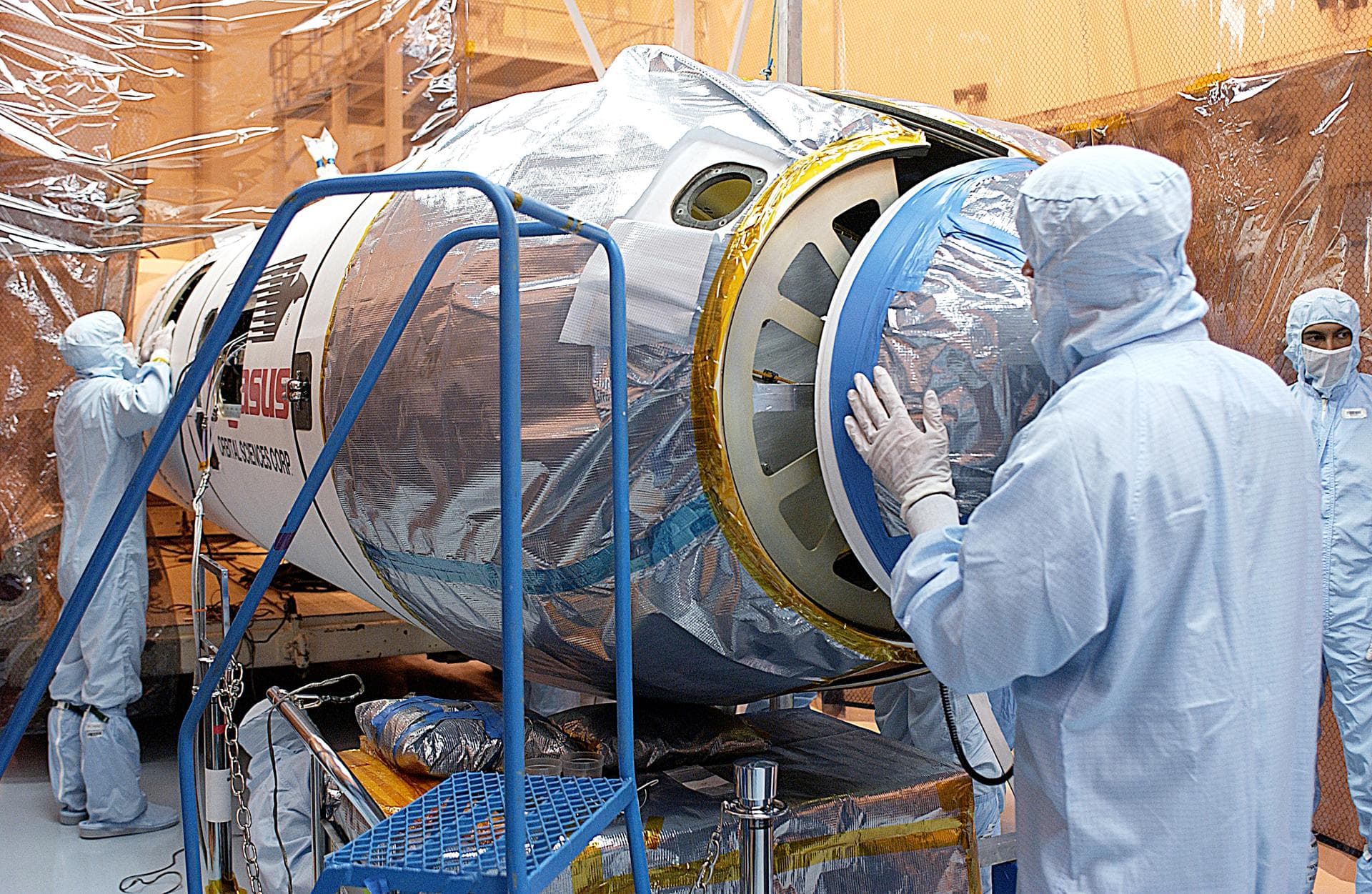 Workers in the Multi-Payload Processing Facility prepare to close the port fairing around the Galaxy Evolution Explorer (GALEX). The spacecraft is already mated to the Pegasus launch vehicle. After en