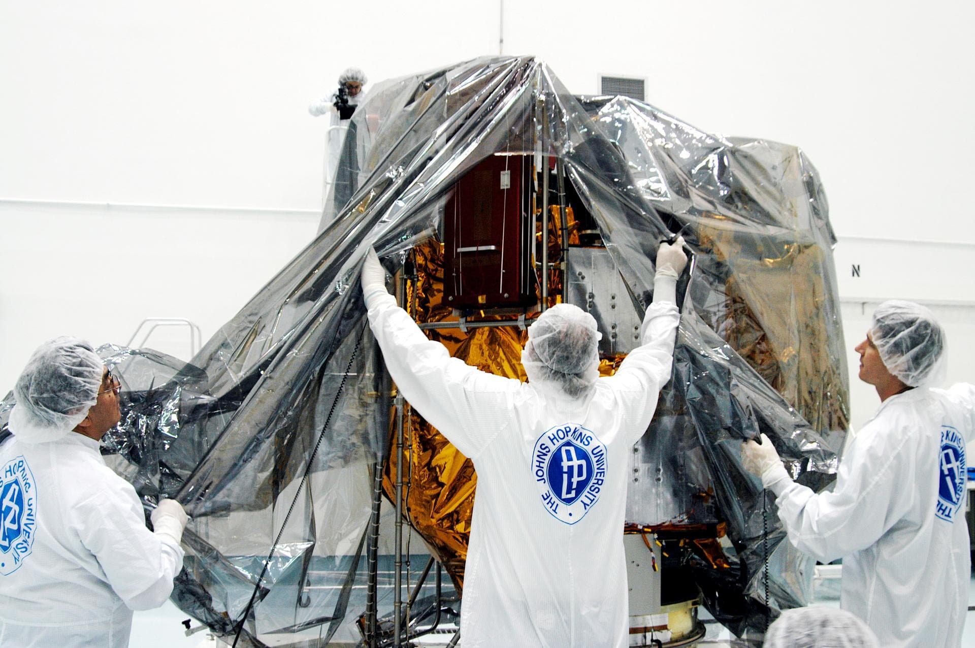 KENNEDY SPACE CENTER, FLA. -  In the high bay clean room at the Astrotech Space Operations processing facilities near KSC, workers remove the protective cover from NASA’s MESSENGER spacecraft.  Employ