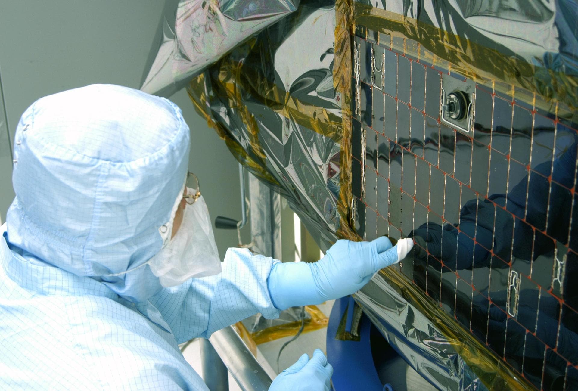 KENNEDY SPACE CENTER, FLA. -  In the clean room at NASA’s Hangar AE on Cape Canaveral Air Force Station (CCAFS), a Spectrolab technician, Anna Herrera,  points to an area on the Swift spacecraft’s sol