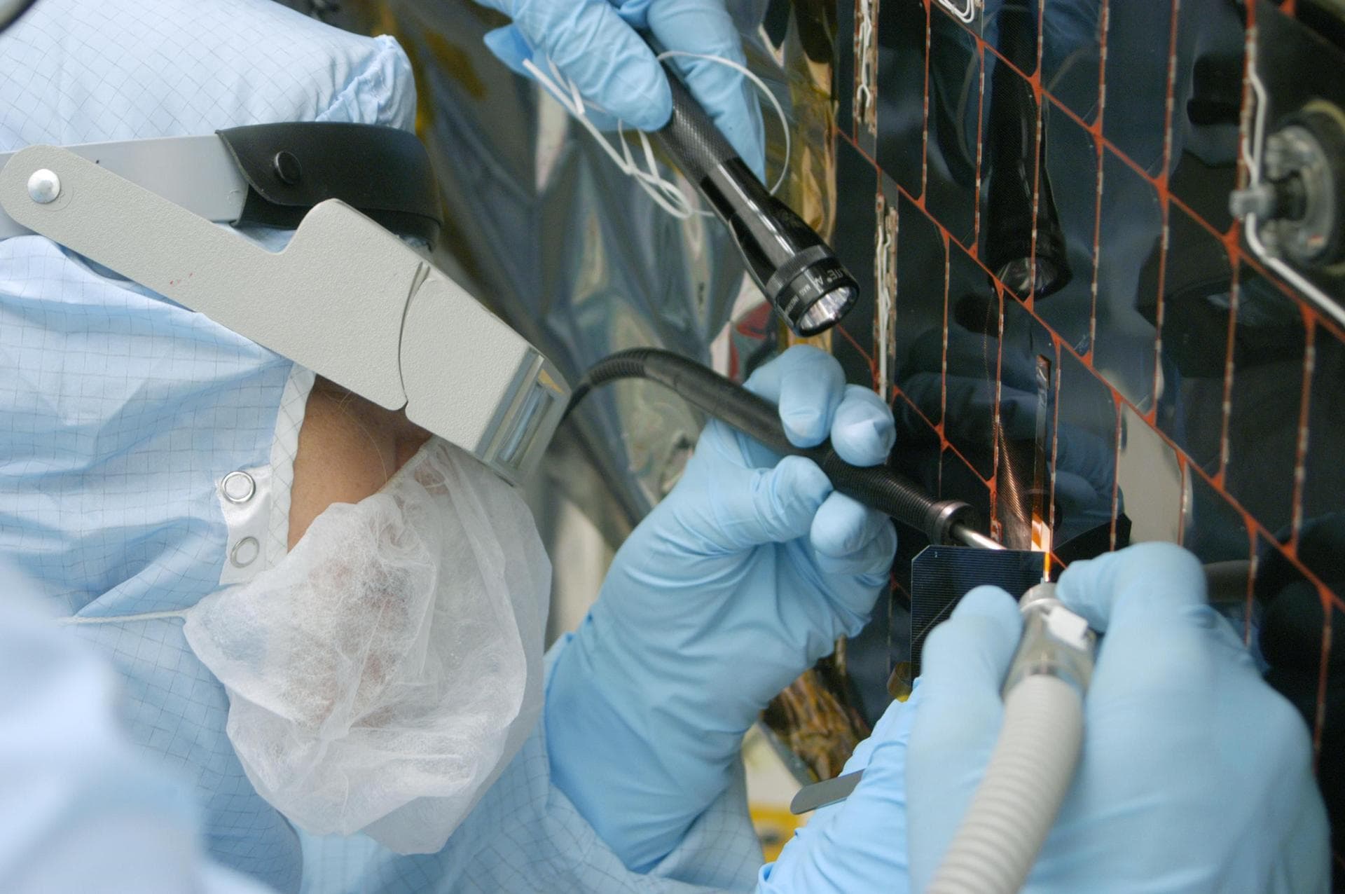 KENNEDY SPACE CENTER, FLA. -  In the clean room at NASA’s Hangar AE on Cape Canaveral Air Force Station (CCAFS), a Spectrolab technician, Anna Herrera,  removes one of the solar cells that will be rep