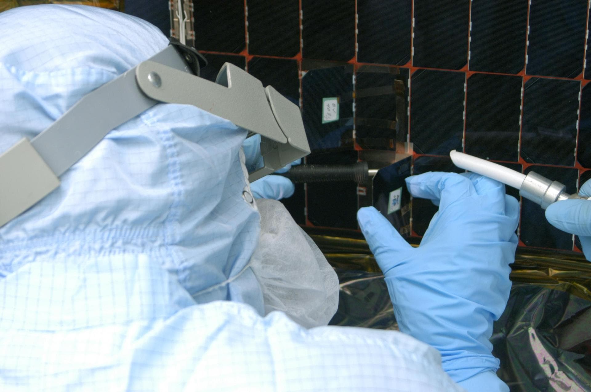 KENNEDY SPACE CENTER, FLA. -  In the clean room at NASA’s Hangar AE on Cape Canaveral Air Force Station (CCAFS), a Spectrolab technician, Anna Herrera,  places a new solar cell on the Swift spacecraft