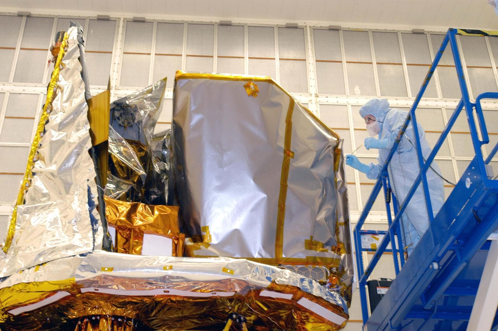 KENNEDY SPACE CENTER, FLA. - Technician Grace Miller-Swales does touch-up work on the Swift spacecraft in Hangar AE at Cape Canaveral Air Force Station. Swift is wrapped with blankets to provide therm