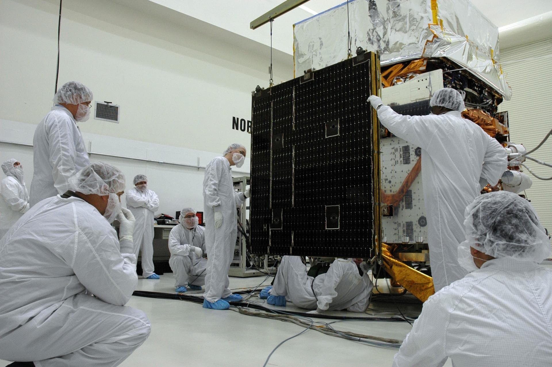 KENNEDY SPACE CENTER, FLA. - In the Astrotech payload processing facility, General Dynamics technicians install the second of twin solar arrays on NASA's Gamma-Ray Large Area Space Telescope, or GLAS