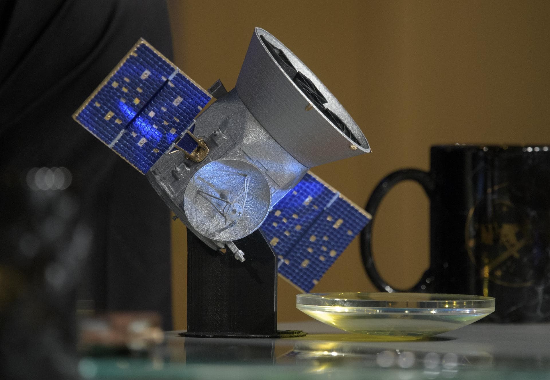 A model of the Transiting Exoplanet Survey Satellite (TESS) and a spare camera lens are seen during a media briefing, Wednesday, March 28, 2018 at NASA Headquarters in Washington. Photo Credit: (NASA/