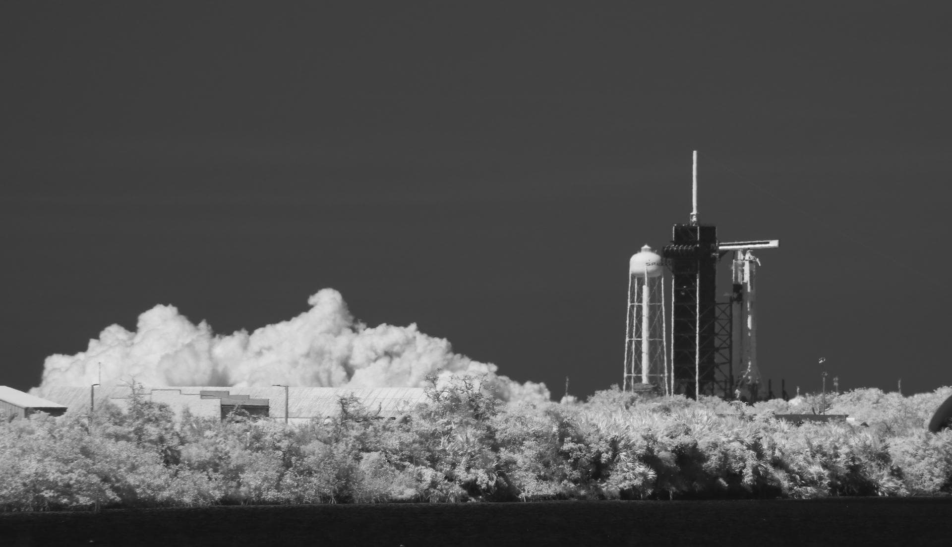 In this black and white infrared image, a SpaceX Falcon 9 rocket with the company's Crew Dragon spacecraft onboard is seen on the launch pad at Launch Complex 39A during a brief static fire test ahead