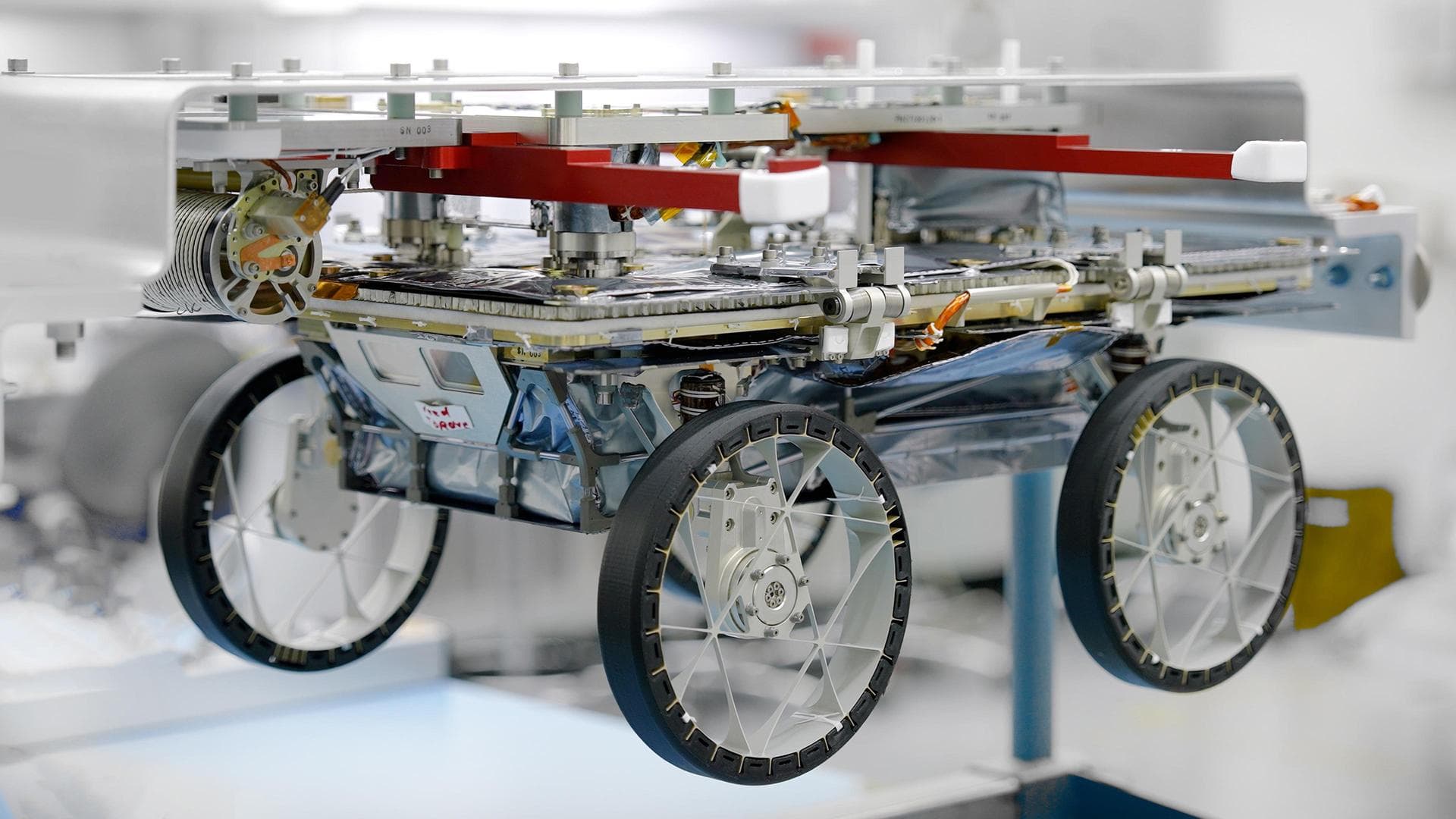       One of three small lunar rovers that are part of a NASA technology demonstration called CADRE (Cooperative Autonomous Distributed Robotic Exploration) is attached to a fixture in a clean room at