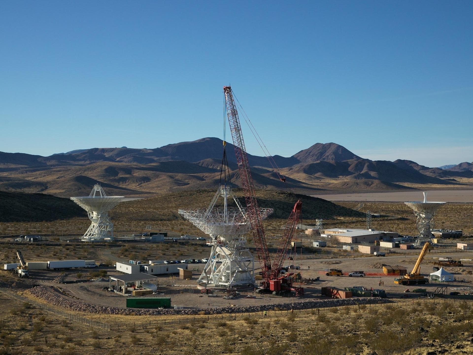 A crane lowers a four-legged support structure called a quadripod onto the steel framework of the Deep Space Station 23 (DSS-23) reflector dish on Dec. 18, 2024. The reflector framework was bolted int