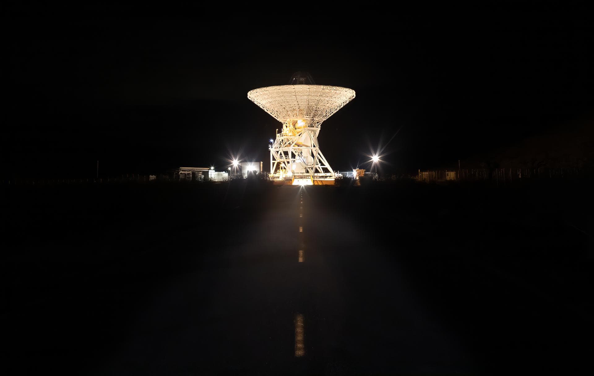 A 112-foot (34-meter) antenna glows from within a nighttime scene at the Goldstone Deep Space Communications Complex near Barstow, California, in September 2025. Goldstone is part of NASA’s Deep Spa