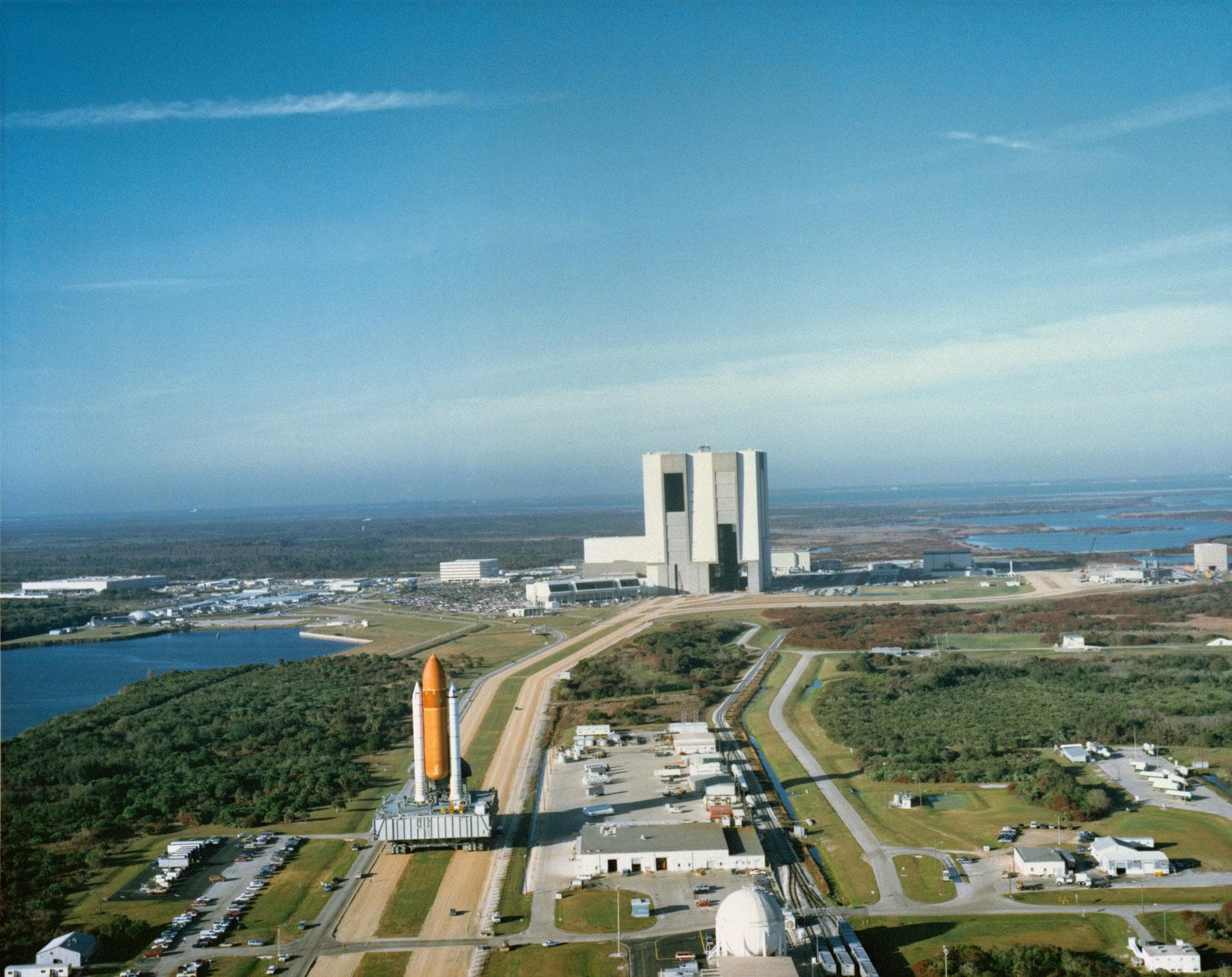 Atlantis, Orbiter Vehicle (OV) 104, is blocked by its large orange external tank (ET) as it leaves Vehicle Assembly Building (VAB) during its rollout to Kennedy Space Center (KSC) Launch Complex (LC) 