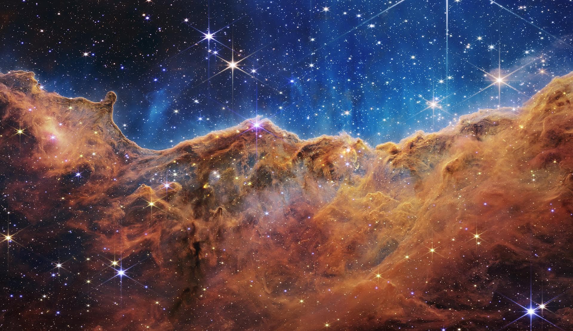 What looks much like craggy mountains on a moonlit evening is actually the edge of a nearby, young, star-forming region NGC 3324 in the Carina Nebula. Captured in infrared light by the Near-Infrared C