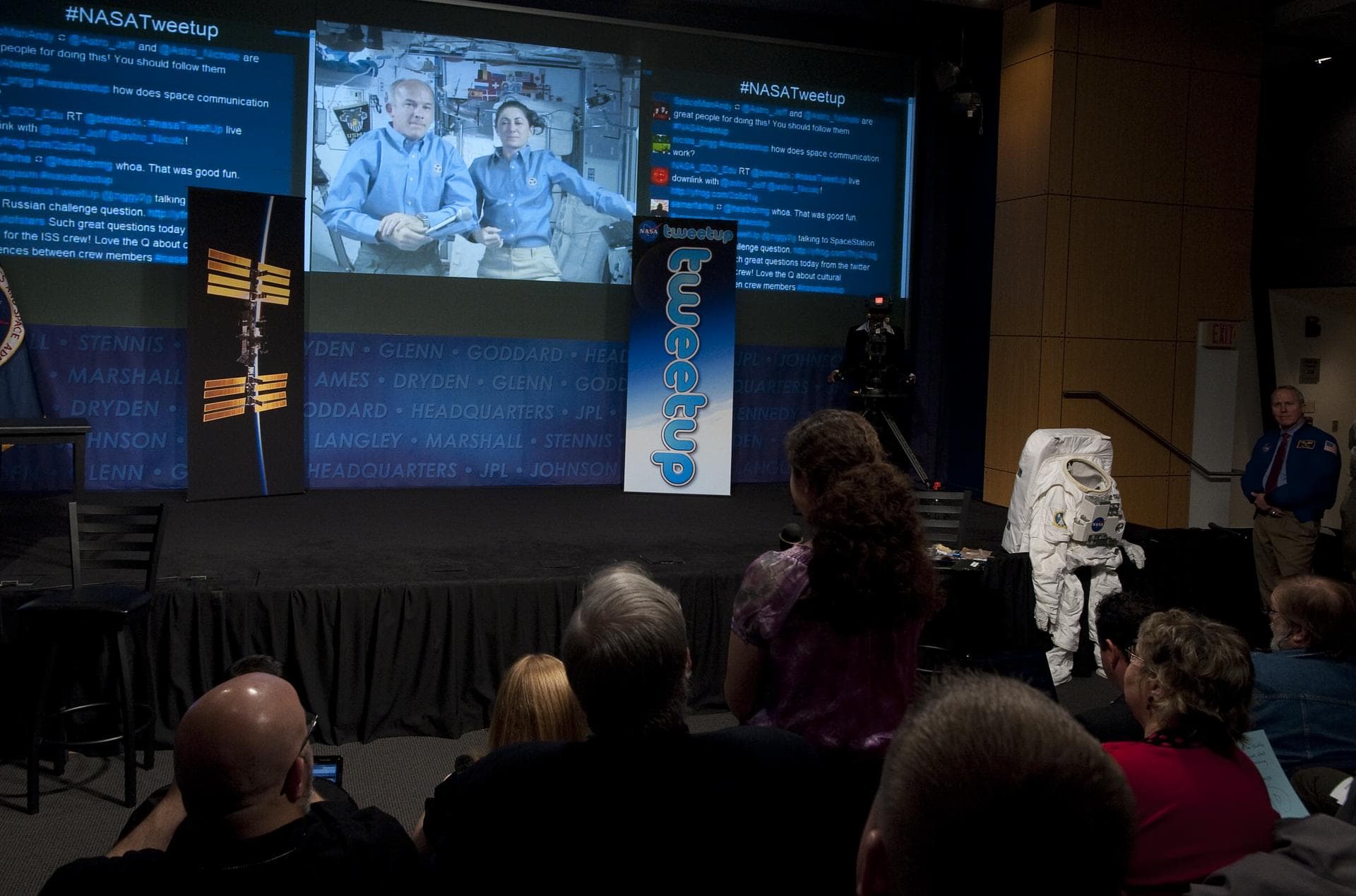 Expedition 20 Flight Engineers Jeff Williams, left, and Nicole Stott, seen on screen, are asked a question by a NASA Twitter follower, center, during a question and answer session at a live Tweetup ev