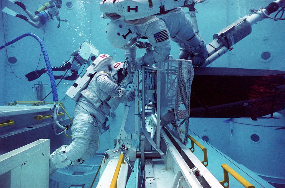 Astronauts Mark Lee and Rich Clifford perform test check-out procedures on the Hubble Space Telescope in the Marshall Space Flight Center's Neutral Buoyancy Simulator (NBS).