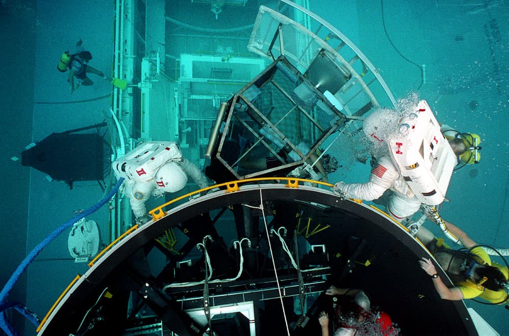 Astronauts Jim Voss and Jay Apt perform check-out procedures on a Hubble Space Telescope mock-up while working in the Marshall Space Flight Center's Neutral Buoyancy Simulator (NBS).