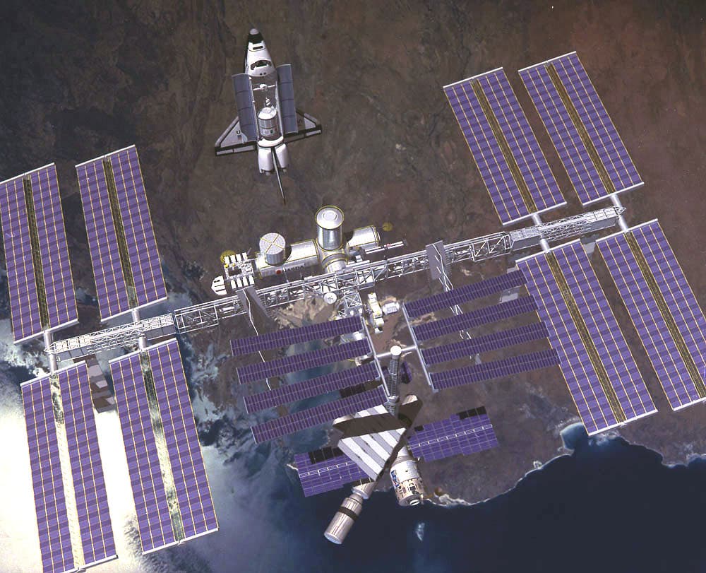 An artist's concept of Phase III of the International Space Station (ISS) with the Shuttle approaching.