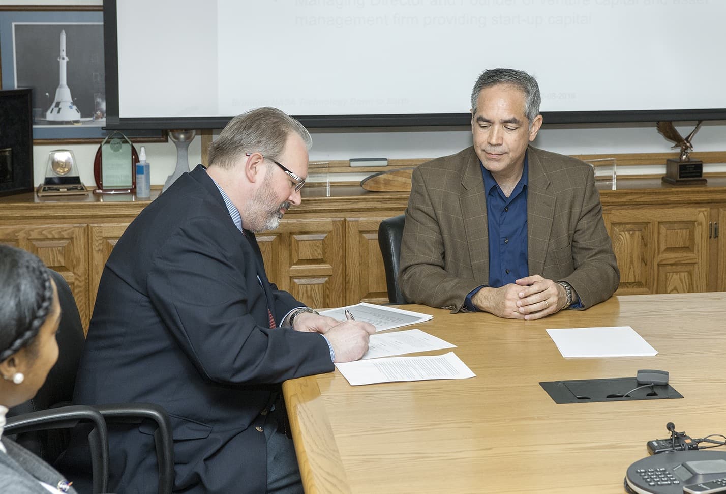 Vigilant Aerospace Systems CEO Kraettli Epperson, left, and NASA Armstrong Flight Research Center Director David McBride, sign the agreement for the company to commercialize a large drone communicatio
