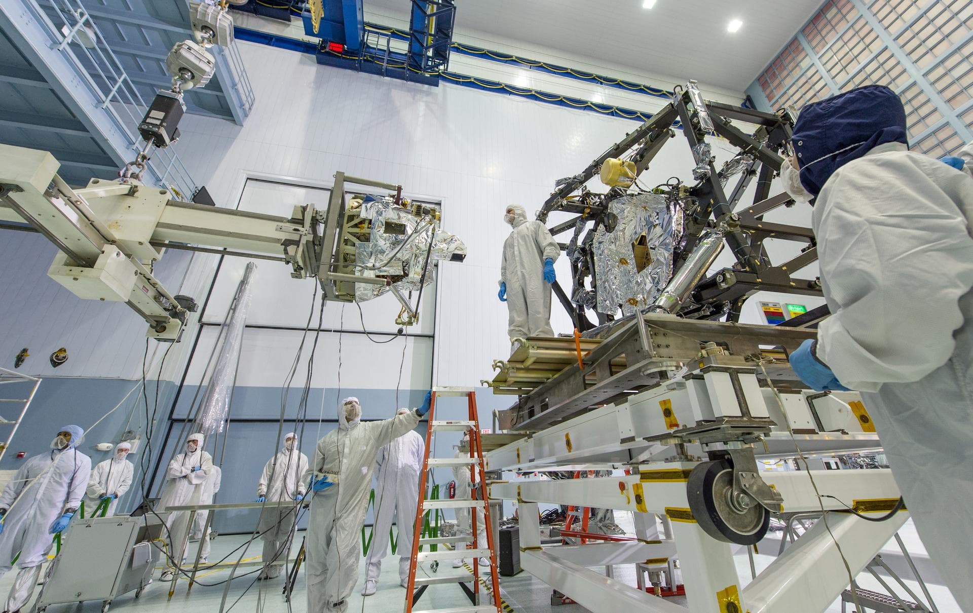 The MIRI itself weighs 181 pounds (82 kg) and is being held by a special balance beam (on the left of the photo), which is being maneuvered using a precision overhead crane by the engineer at the base