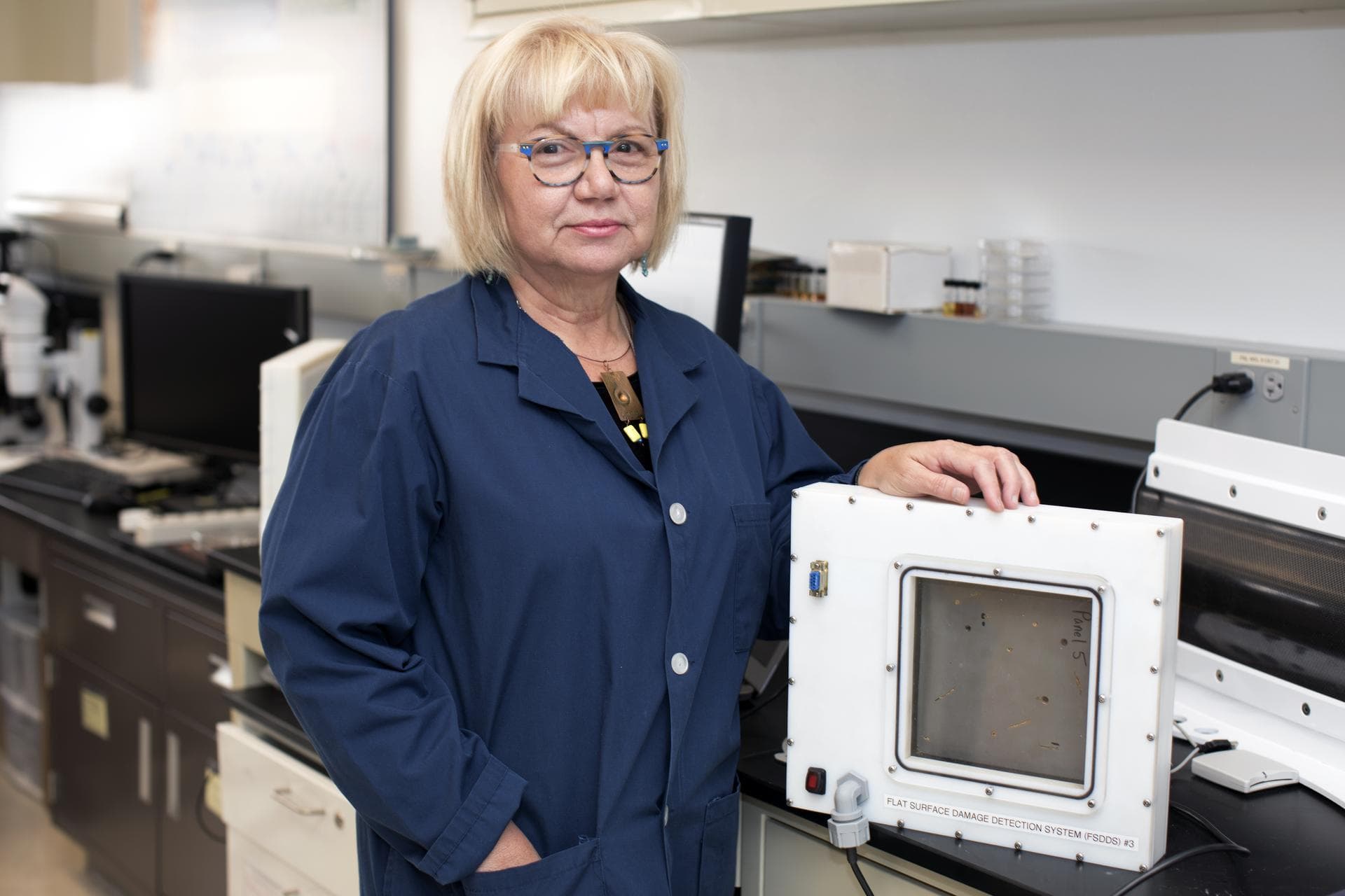 Martha Williams, who leads the team inventing the Flexible Damage Detection System, stands in a laboratory with a prototype at NASA's Kennedy Space Center in Florida. The system uses circuits printed