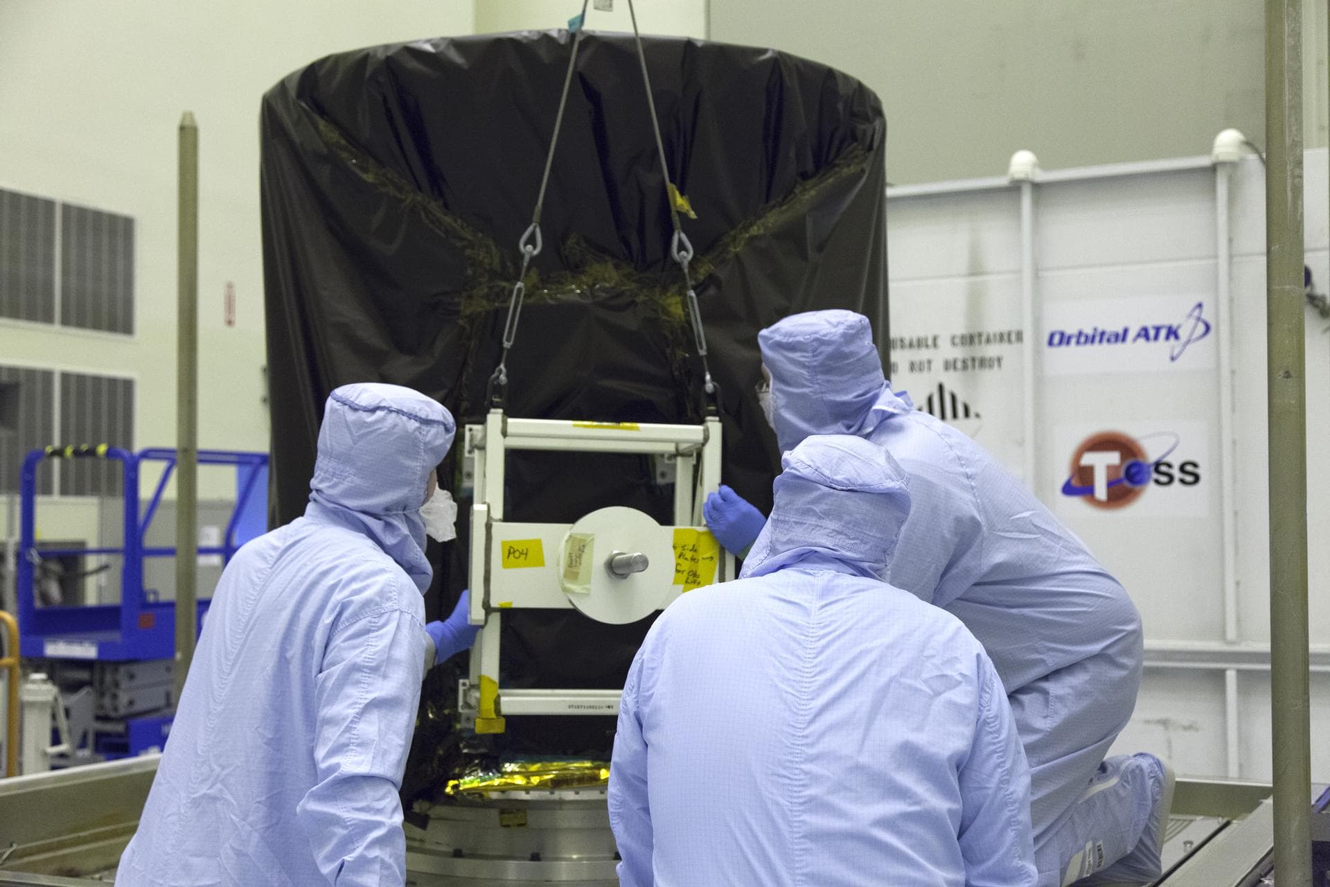 NASA's Transiting Exoplanet Survey Satellite (TESS) is lifted up from the base of its shipping container and will be lowered onto a test stand for processing inside the Payload Hazardous Servicing Fac