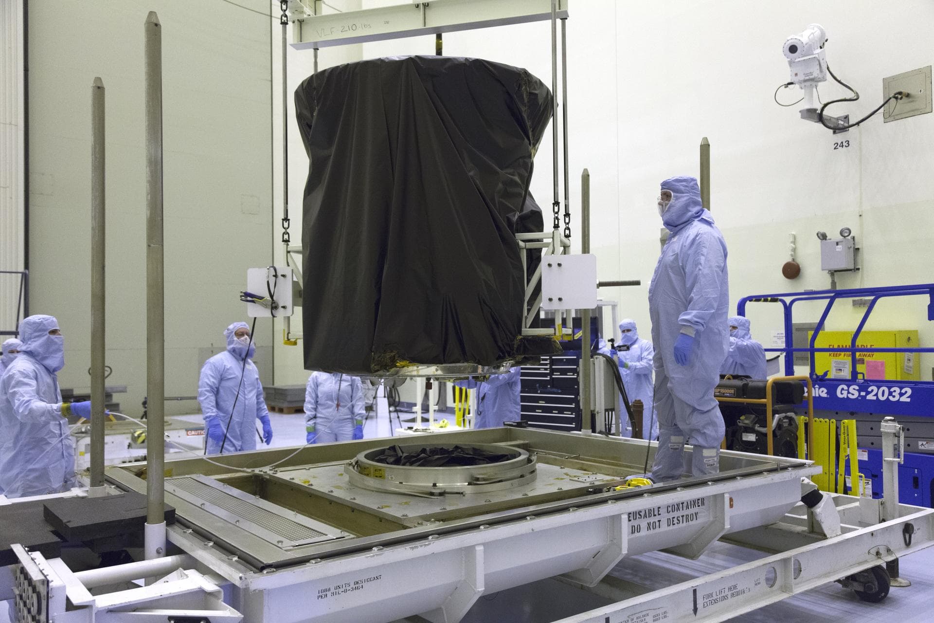 NASA's Transiting Exoplanet Survey Satellite (TESS) is lifted up from the base of its shipping container and will be lowered onto a test stand for processing inside the Payload Hazardous Servicing Fac