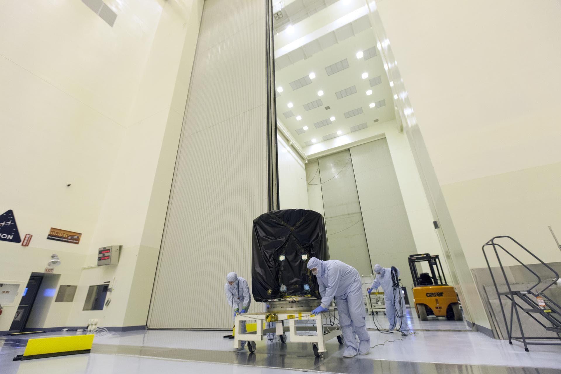 Technicians dressed in clean room suits move NASA's Transiting Exoplanet Survey Satellite (TESS) on a test stand inside the Payload Hazardous Servicing Facility (PHSF) at the agency's Kennedy Space Ce