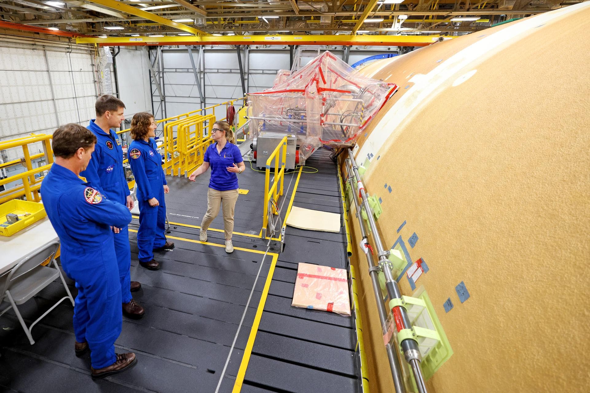 Artemis II NASA astronauts Reid Wiseman and Christina Koch of NASA and CSA (Canadian Space Agency) astronaut Jeremy Hansen view the core stage for the SLS (Space Launch System) rocket at the agency’s