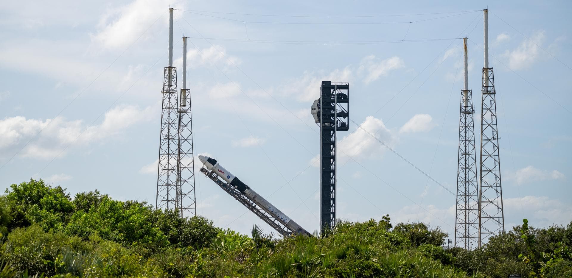 A SpaceX Falcon 9 rocket with the company's Dragon spacecraft on top is seen as it is raised into a vertical position on the launch pad at Space Launch Complex 40 as preparations continue for the Crew