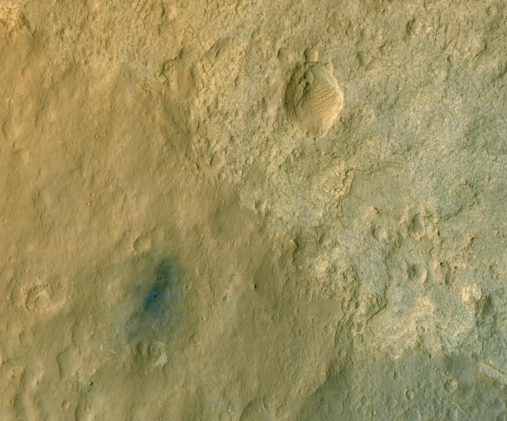 This color-enhanced view of NASA Curiosity rover on the surface of Mars was taken by NASA Mars Reconnaissance Orbiter as the satellite flew overhead. The descent stage blast pattern around the rover i