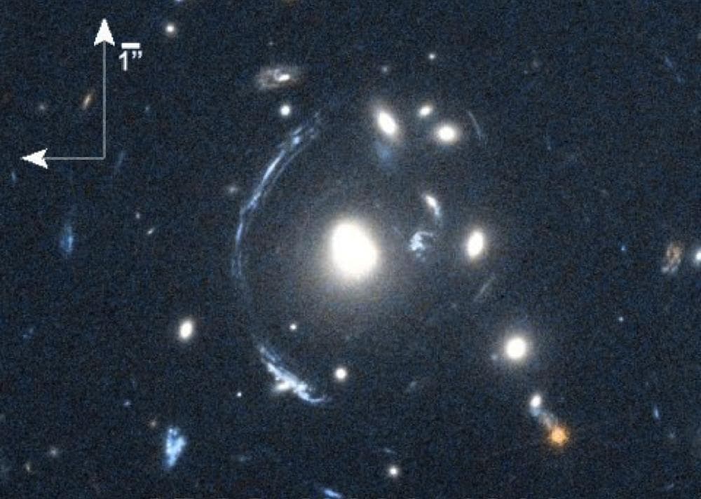 The young galaxy SDSS090122.37+181432.3, also known as S0901, is seen here by the Herschel Space Observatory and the Hubble Space Telescope as the bright arc to the left of the central bright galaxy.