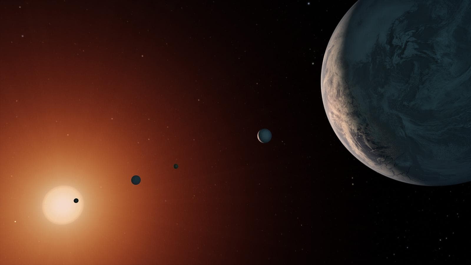 This illustration shows what the TRAPPIST-1 system might look like from a vantage point near planet TRAPPIST-1f (at right). The system has been revealed through observations from NASA's Spitzer Space