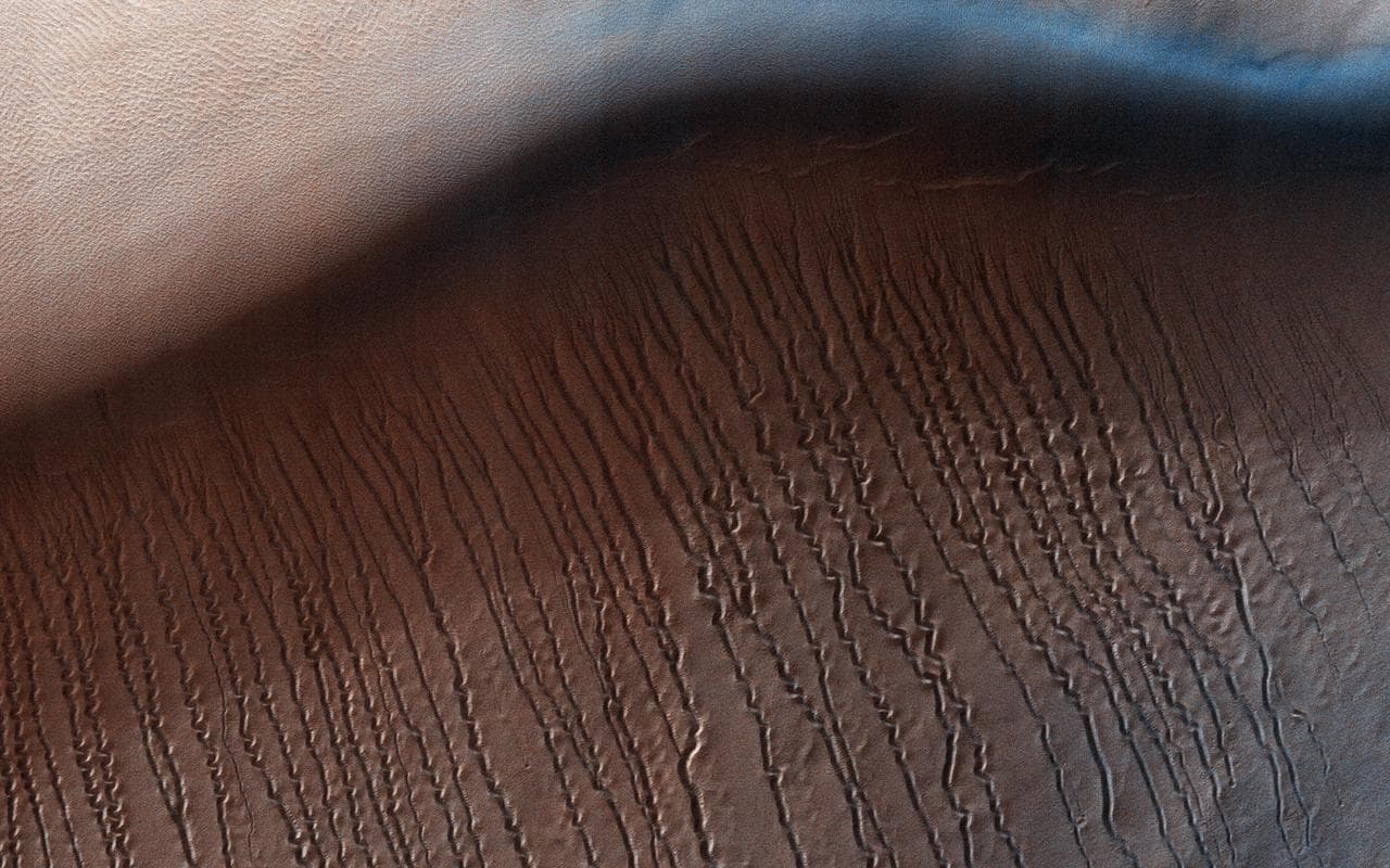 At around 2,200 kilometers in diameter, Hellas Planitia is the largest visible impact basin in the Solar System, and hosts the lowest elevations on Mars' surface as well as a variety of landscapes. Th