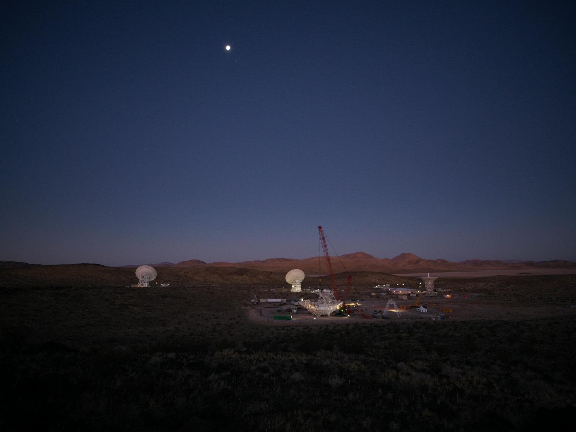 In the early morning of Dec. 18, 2024, a crane looms over the 112-foot-wide (34-meter-wide) steel framework for Deep Space Station 23 (DSS-23) reflector dish, which will soon be lowered into pos