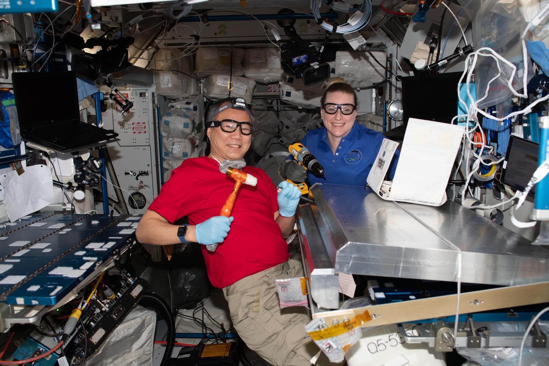 iss064e053432 (April 6, 2021) --- Expedition 64 Flight Engineers Soichi Noguchi of the Japan Aerospace Exploration Agency and Kate Rubins of NASA configure a radiation shield for temporary sleeping qu