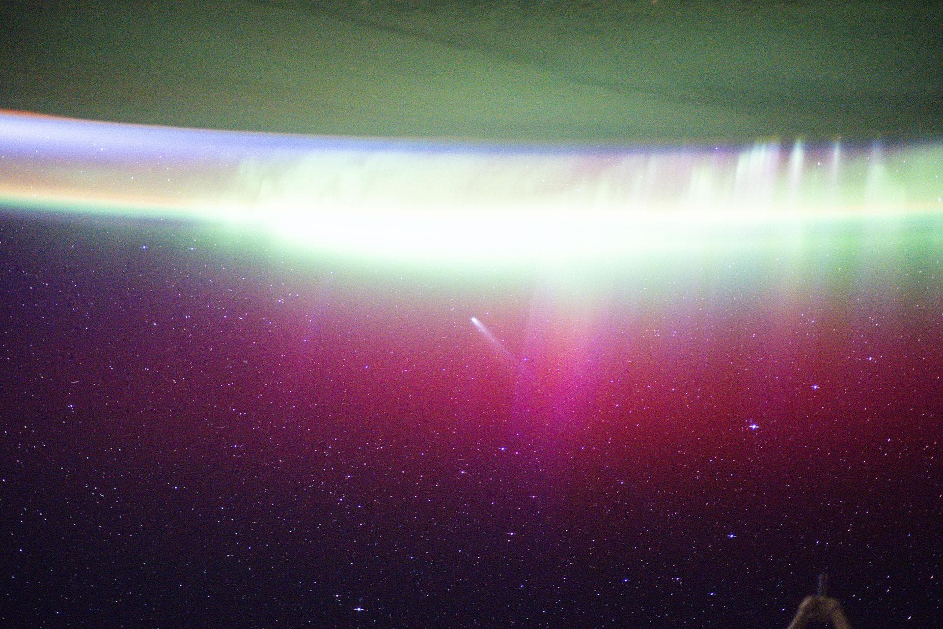 iss073e0981051 (Oct. 24, 2025) --- A bright, neon-like aurora radiates above Earth, seemingly absorbing Comet Lemmon (C/2025 A6) as it soars past the planet at a distance of about 57.2 million miles (