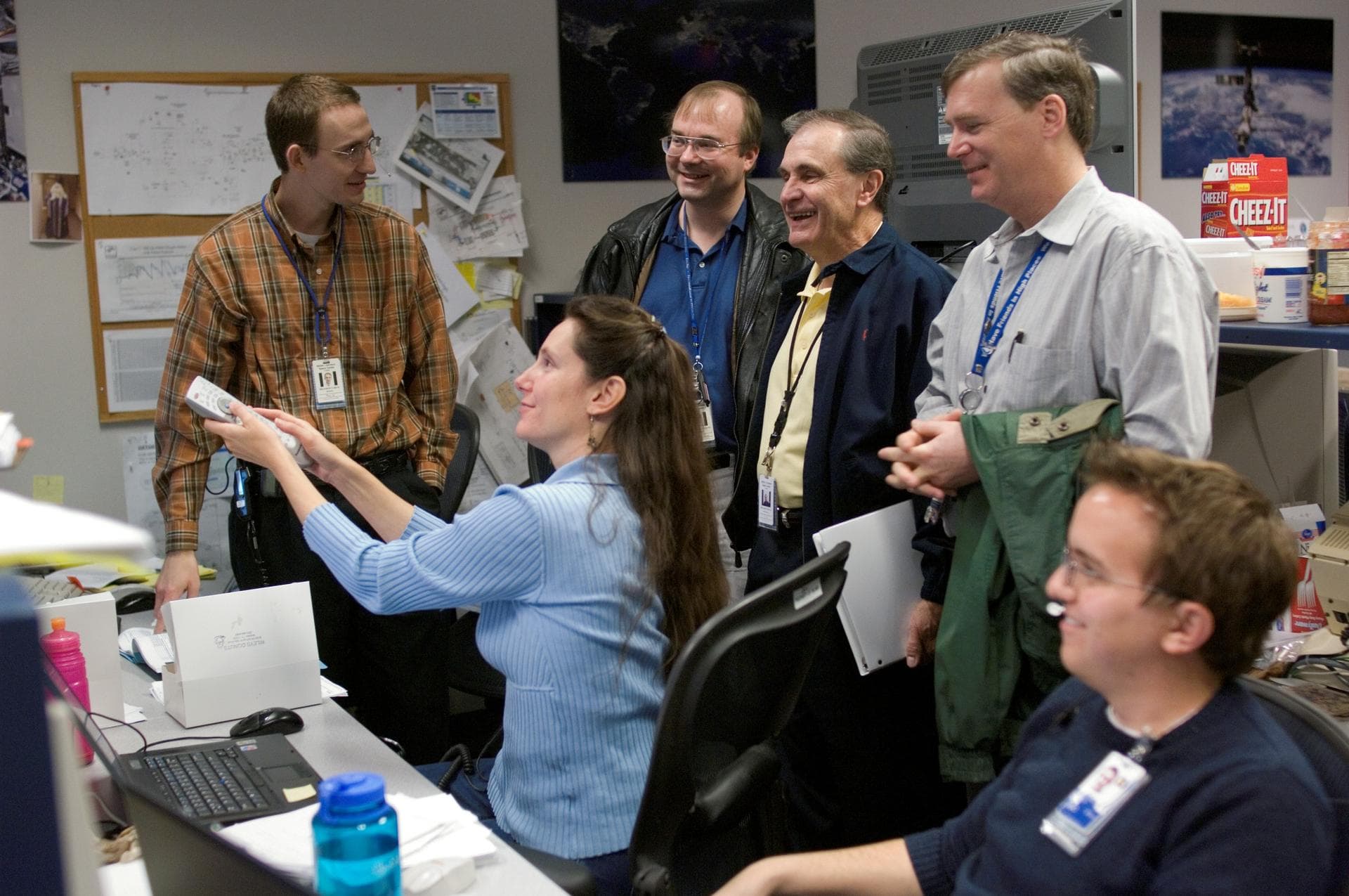 JSC2006-E-54262 ( ) --- MERLIN console operators review the Environmental Control and Life Support (ECLS) system status with ECLS management in preparation for the IMMT. Standing, from the left, are