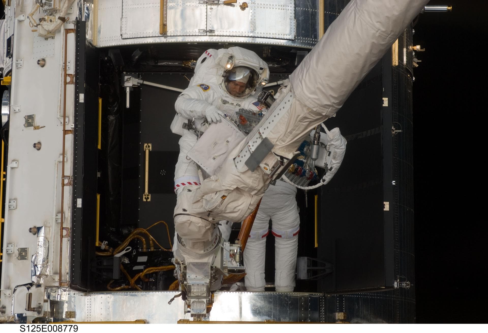 S125-E-008779 (17 May 2009) --- Astronauts Michael Good and Mike Massimino (partially obscured), both STS-125 mission specialists, participate in the mission?s fourth session of extravehicular activit