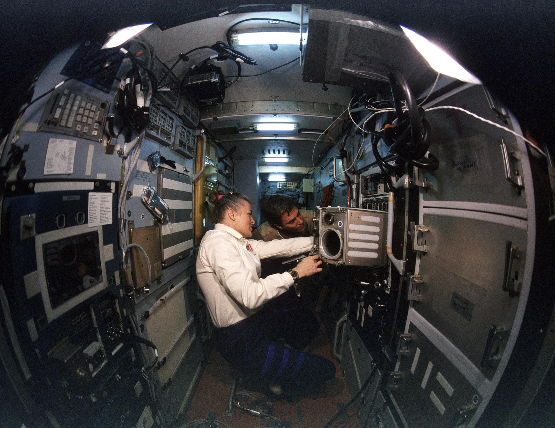 STS079-S-092 (16-26 Sept. 1996) --- Astronauts Shannon W. Lucid and John E. Blaha work at a microgravity glove box on the Priroda Module aboard Russia's Mir Space Station complex. Blaha, who flew into